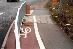 Image of a cycle path painted on a road with a metal fence running the length of it, dividing it in half